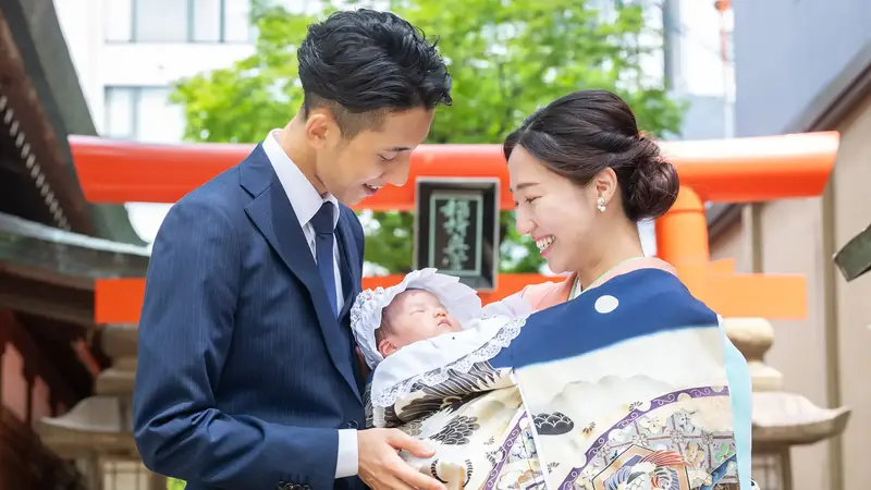 鳥居の前で祝い着姿の赤ちゃんを抱いて並ぶご両親