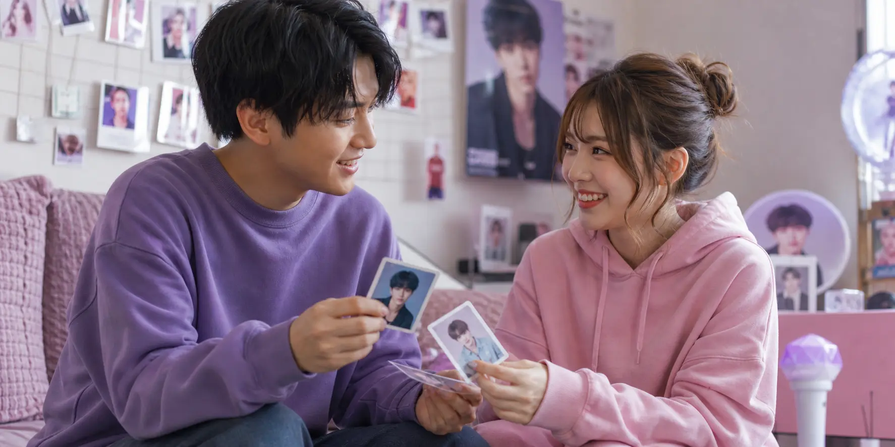 男女2人のファンが推しの写真カードを見せ合って楽しむ推し活シーン