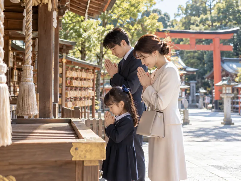 受験を控えた家族が神社の拝殿で手を合わせて合格祈願をする様子